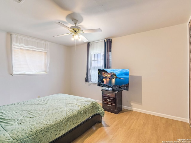 bedroom featuring ceiling fan, light hardwood / wood-style flooring, and multiple windows