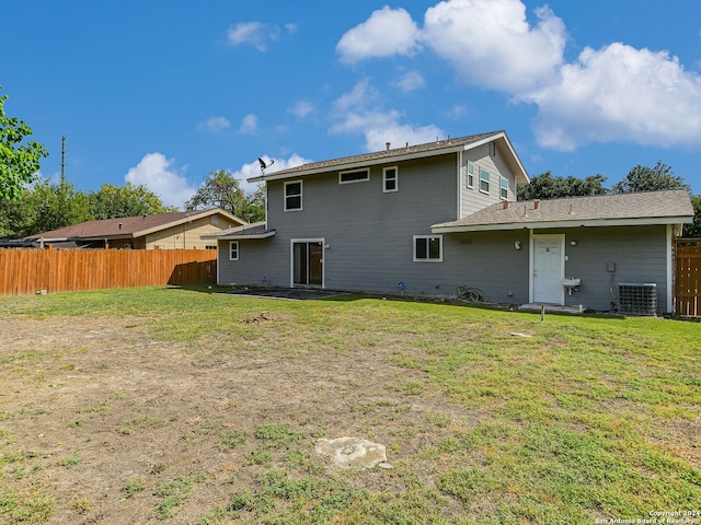 rear view of property with cooling unit and a yard