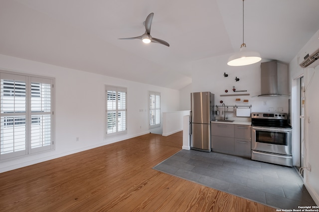 kitchen featuring gray cabinetry, wall chimney range hood, stainless steel appliances, vaulted ceiling, and dark hardwood / wood-style flooring