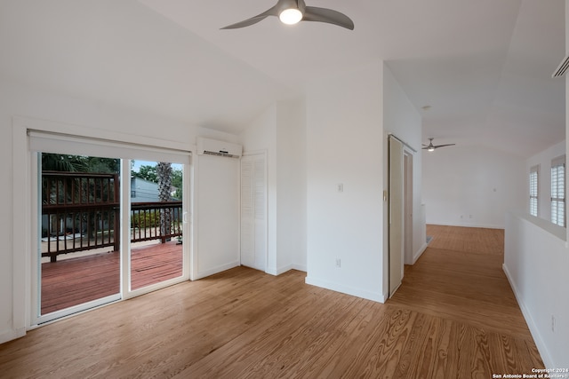 spare room featuring lofted ceiling, ceiling fan, a wall unit AC, and light hardwood / wood-style flooring