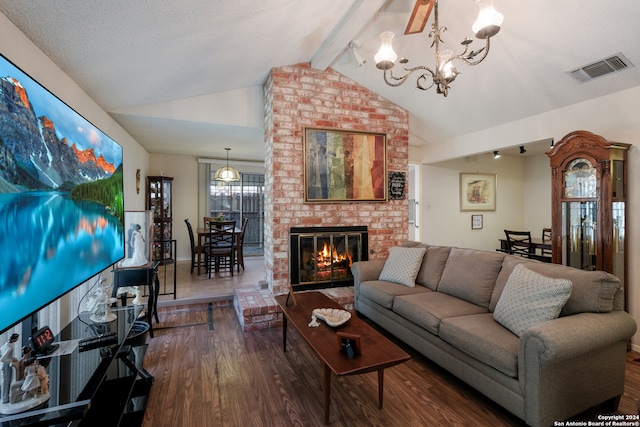 living room with a chandelier, a textured ceiling, hardwood / wood-style flooring, a brick fireplace, and vaulted ceiling with beams