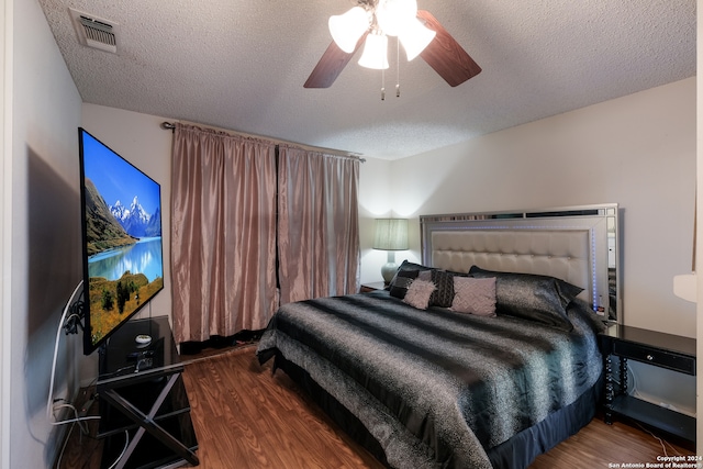 bedroom with ceiling fan, hardwood / wood-style flooring, and a textured ceiling