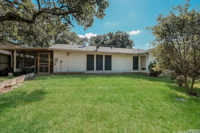 rear view of property featuring a lawn and a sunroom