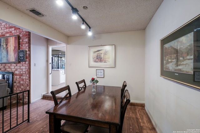 dining space with wood-type flooring, a textured ceiling, and track lighting