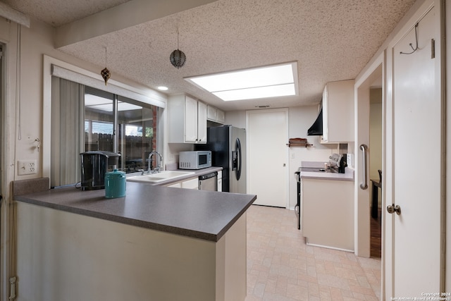 kitchen featuring white cabinetry, kitchen peninsula, stainless steel appliances, sink, and wall chimney range hood