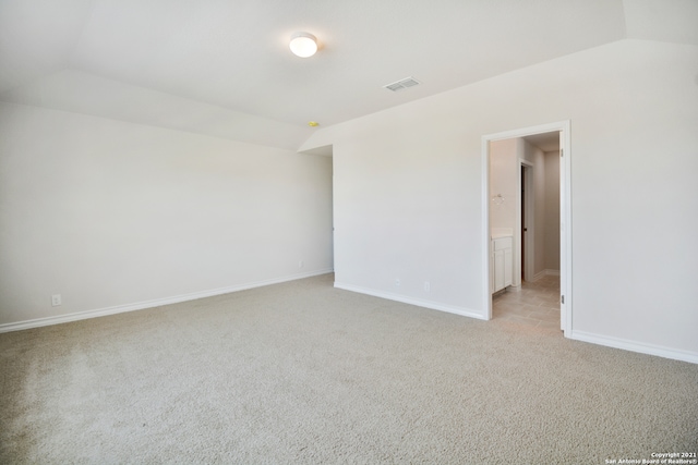 carpeted empty room with vaulted ceiling