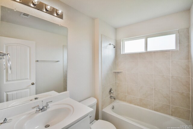 full bathroom featuring vanity, tiled shower / bath combo, and toilet