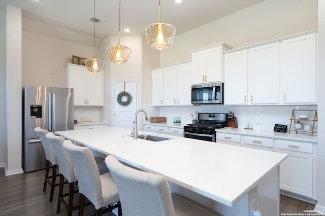 kitchen featuring pendant lighting, white cabinets, sink, a center island with sink, and appliances with stainless steel finishes