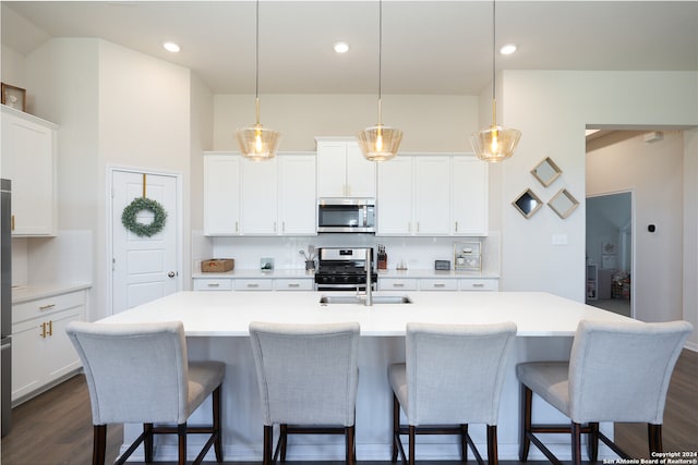 kitchen featuring an island with sink, dark hardwood / wood-style floors, pendant lighting, and stainless steel appliances