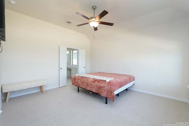 bedroom featuring ceiling fan, ensuite bathroom, light carpet, and vaulted ceiling