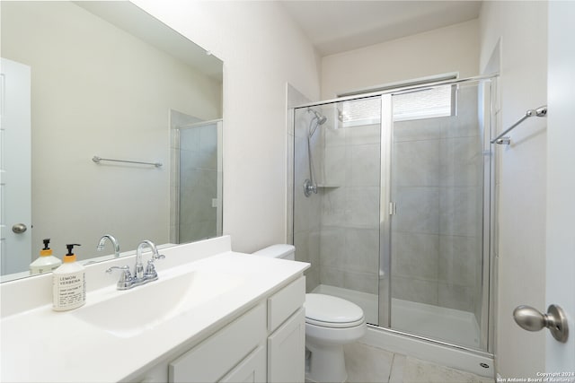 bathroom featuring tile patterned flooring, a shower with shower door, vanity, and toilet