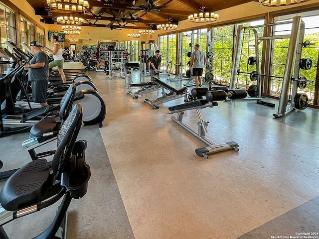 workout area with lofted ceiling, concrete floors, and a notable chandelier