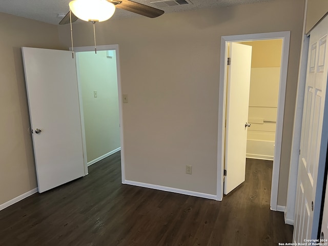 unfurnished bedroom featuring dark wood-type flooring, a textured ceiling, and ceiling fan