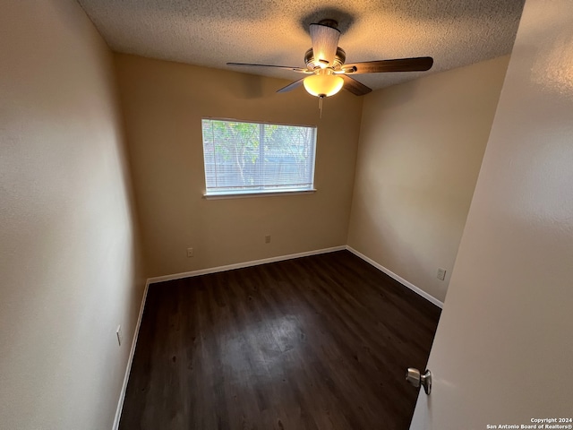 empty room featuring dark wood-type flooring, a textured ceiling, and ceiling fan