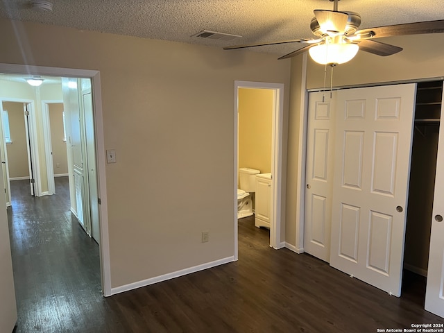 unfurnished bedroom with a textured ceiling, a closet, dark wood-type flooring, ceiling fan, and connected bathroom