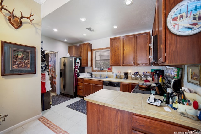 kitchen featuring sink, kitchen peninsula, stainless steel appliances, tile countertops, and light tile patterned floors