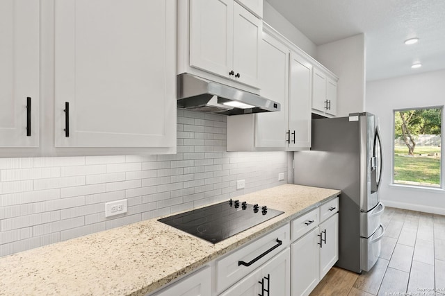 kitchen featuring black electric cooktop, light wood-type flooring, white cabinetry, and light stone counters