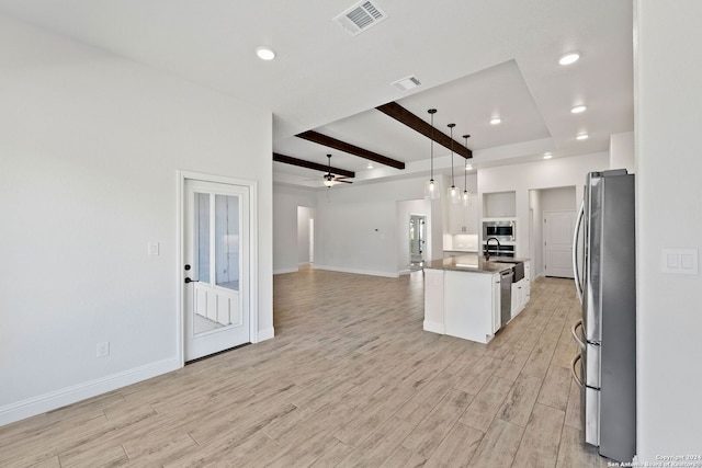 kitchen featuring light hardwood / wood-style floors, white cabinets, stainless steel appliances, a center island with sink, and decorative light fixtures