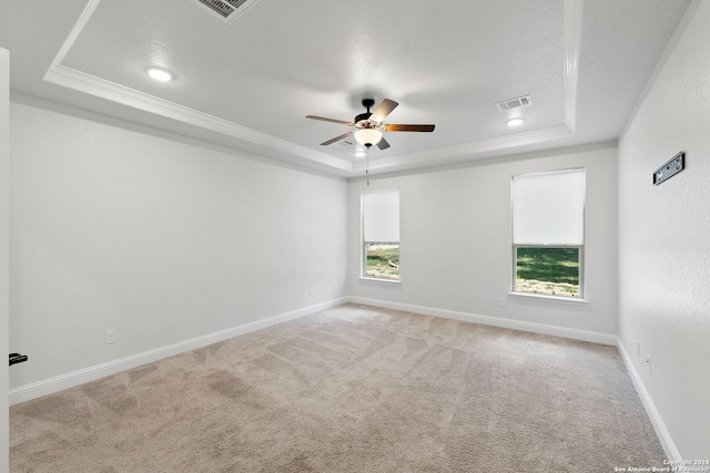 carpeted empty room with a textured ceiling, a raised ceiling, crown molding, and ceiling fan