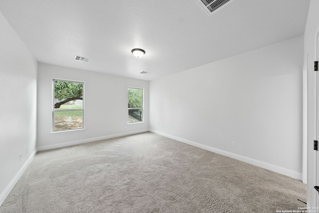 spare room with light colored carpet and a textured ceiling