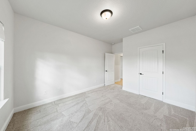 unfurnished bedroom with a textured ceiling, light colored carpet, and a closet