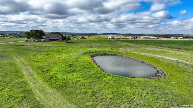 view of community with a rural view, a lawn, and a water view