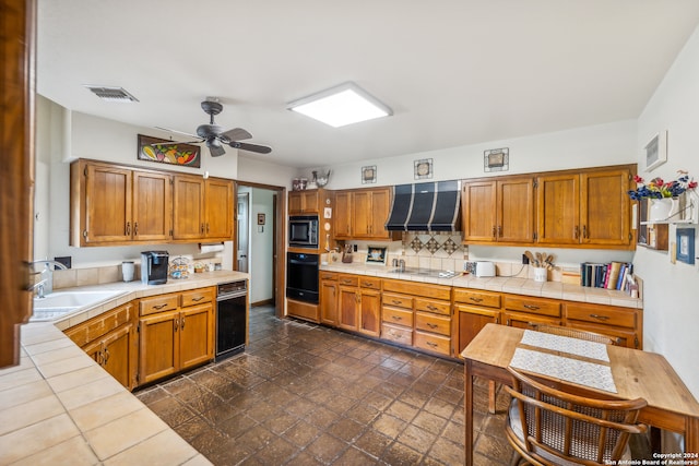 kitchen featuring ceiling fan, custom exhaust hood, sink, appliances with stainless steel finishes, and tile counters