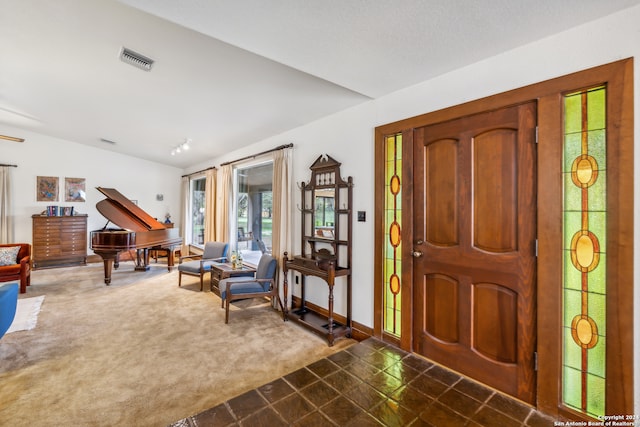 foyer featuring lofted ceiling and carpet