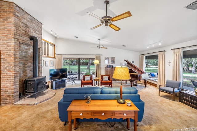 living room featuring ceiling fan, carpet flooring, a wood stove, rail lighting, and vaulted ceiling