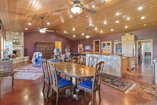 dining area with wooden ceiling, a fireplace, ceiling fan, and concrete flooring