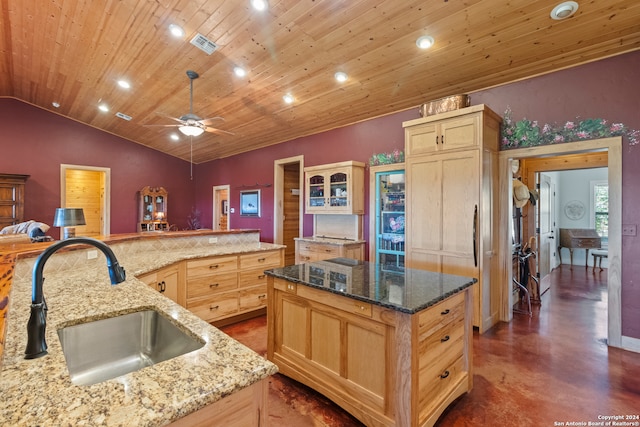 kitchen featuring sink, an island with sink, lofted ceiling, light stone countertops, and ceiling fan