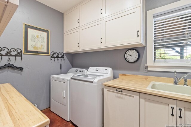 laundry area featuring washer and clothes dryer, sink, and cabinets