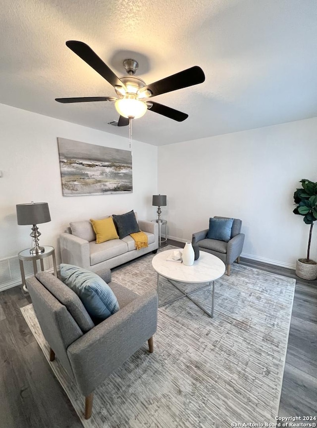 living room with baseboards, wood finished floors, ceiling fan, and a textured ceiling