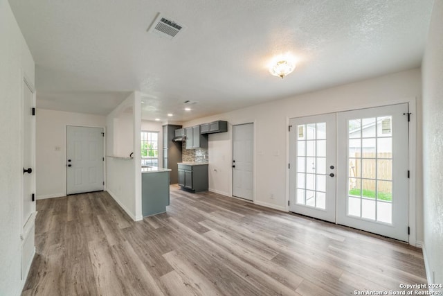 interior space featuring light wood finished floors, baseboards, visible vents, and french doors