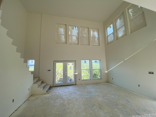 unfurnished living room featuring french doors and a towering ceiling