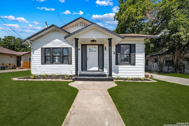 bungalow-style home with central AC unit and a front yard