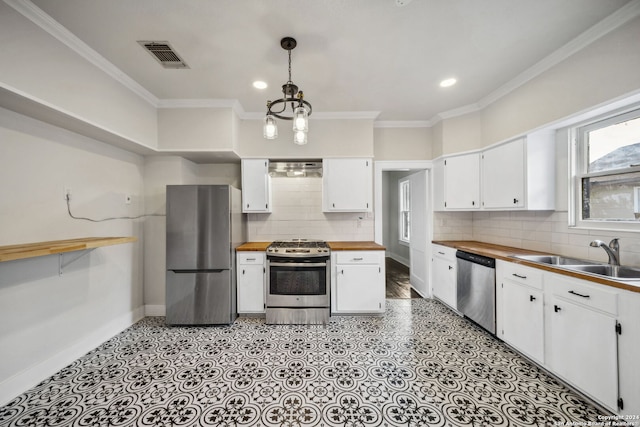 kitchen with pendant lighting, a chandelier, white cabinetry, appliances with stainless steel finishes, and ornamental molding