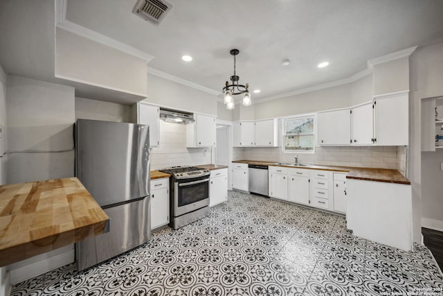 kitchen with pendant lighting, white cabinets, appliances with stainless steel finishes, and wood counters