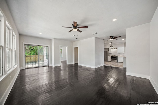 unfurnished living room featuring ceiling fan, a textured ceiling, and dark wood-type flooring