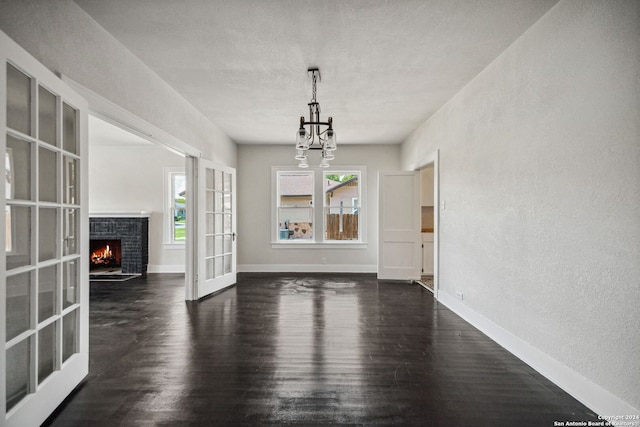 interior space with a fireplace, dark hardwood / wood-style floors, a chandelier, and plenty of natural light