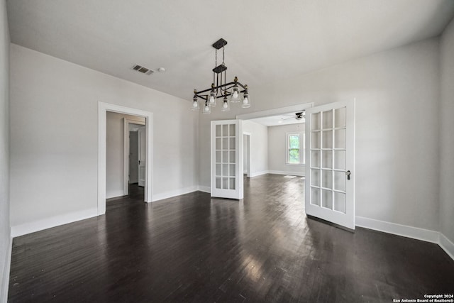 spare room with ceiling fan with notable chandelier, dark hardwood / wood-style floors, and french doors