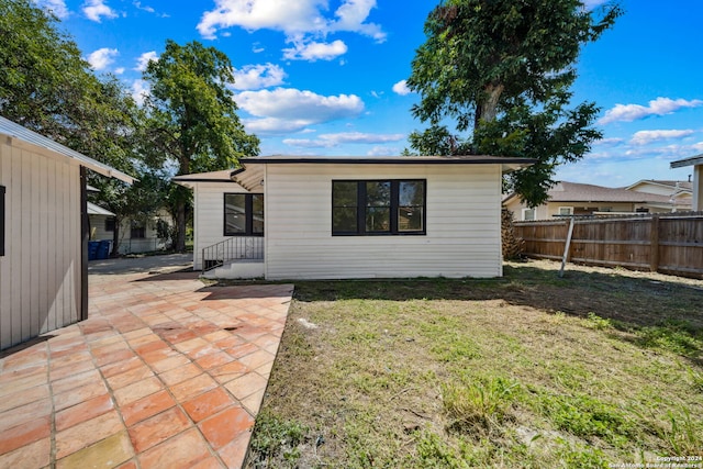 rear view of house featuring a lawn and a patio area