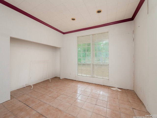 spare room featuring crown molding and light tile patterned floors