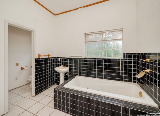 bathroom featuring tile patterned flooring, tiled bath, and toilet