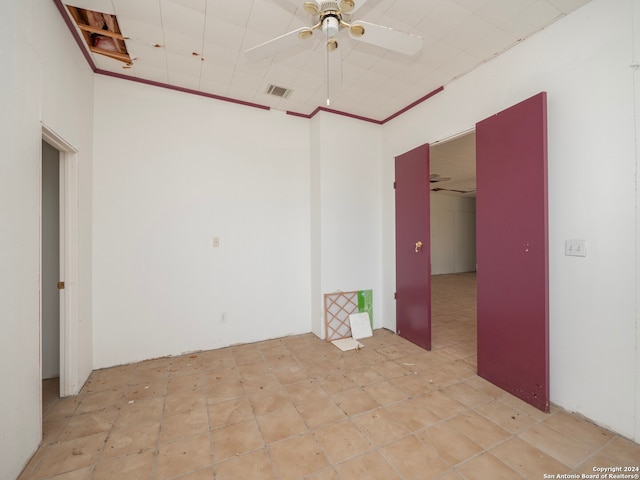 empty room featuring ceiling fan and crown molding