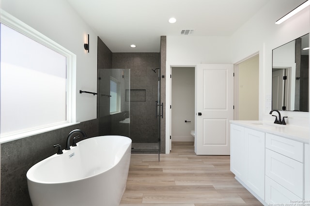 full bathroom with toilet, shower with separate bathtub, vanity, and hardwood / wood-style flooring