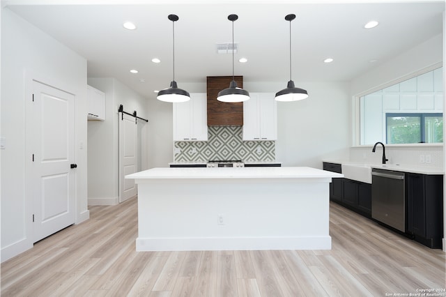 kitchen with a barn door, a center island, white cabinetry, pendant lighting, and stainless steel dishwasher