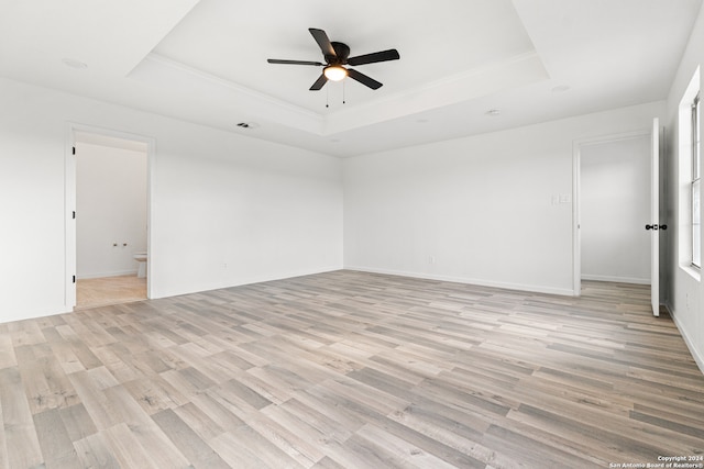 spare room with light wood-type flooring, a raised ceiling, and ceiling fan