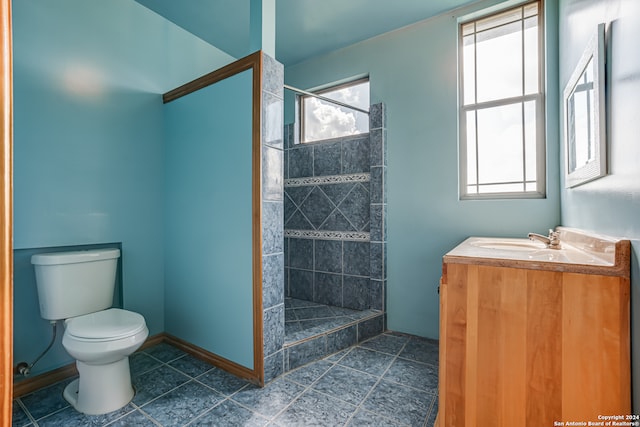 bathroom featuring tiled shower, vanity, toilet, and tile patterned flooring