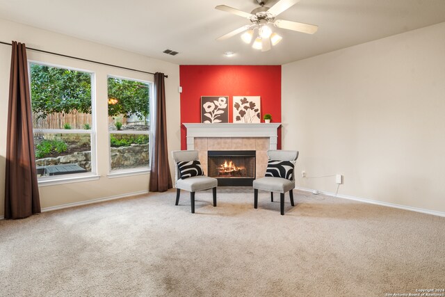 sitting room with carpet, a tiled fireplace, and ceiling fan